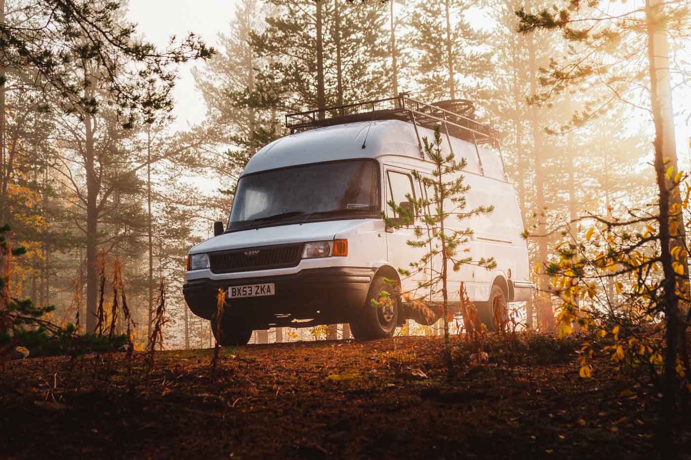 camping in van in misty woodland at the end of autumn