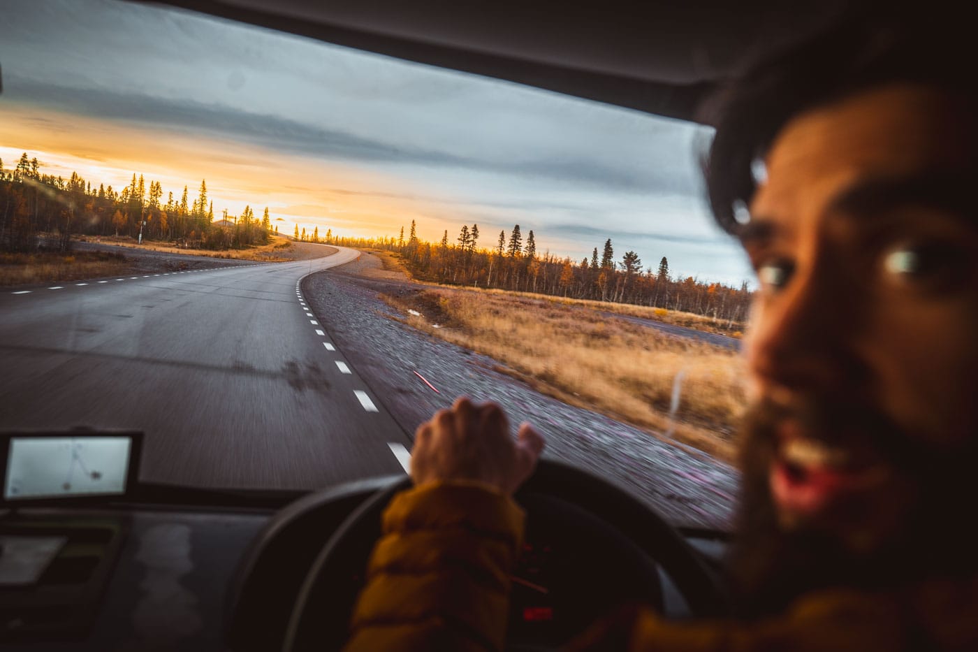 man driving into arctic sunset in sweden