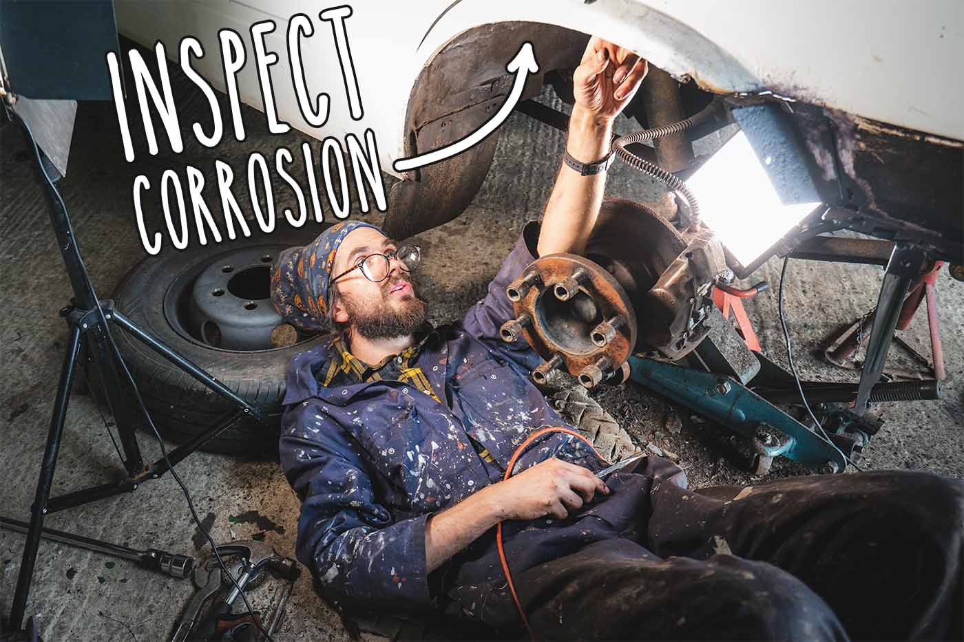 inspecting corrosion under campervan around wheels