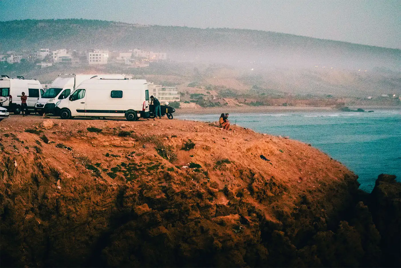 Campervans on top of cliff with coast and sea